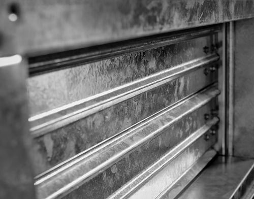 Black-and-white close-up of a metal vent or louvered panel with horizontal slats