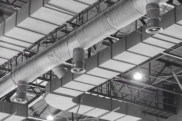 Industrial ceiling with ventilation ducts and hanging lights in a warehouse or factory interior
