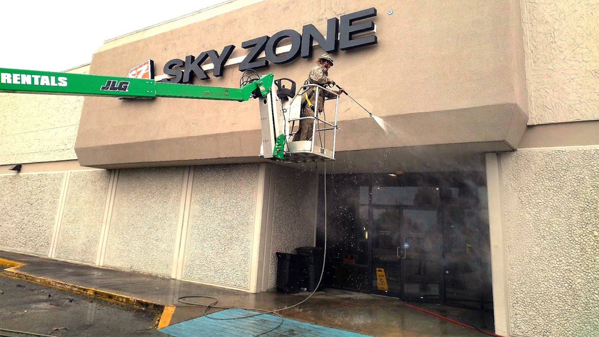 A man is cleaning the sky zone sign on a building