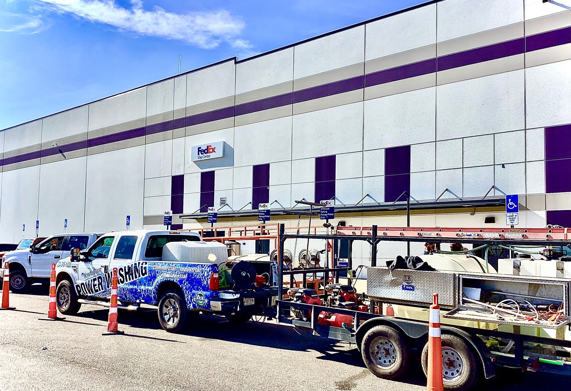 Parking lot with blue and white trucks and trailers beside a large warehouse building.