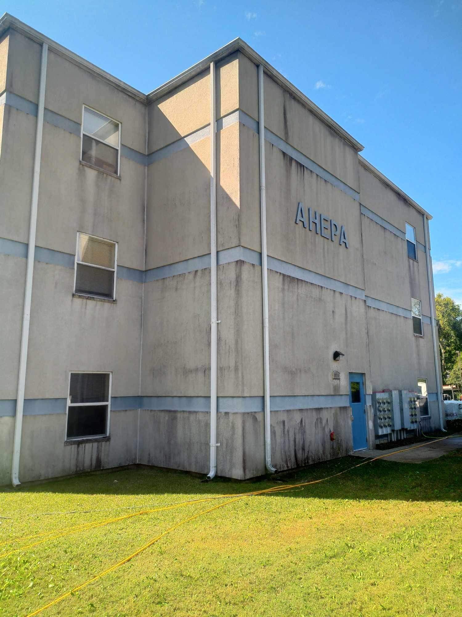 Commercial building with weathered exterior walls, multiple windows, and a blue entrance door