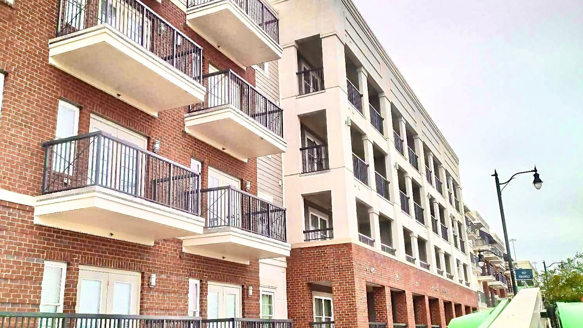 Modern apartment building with brick and white balconies along a city street