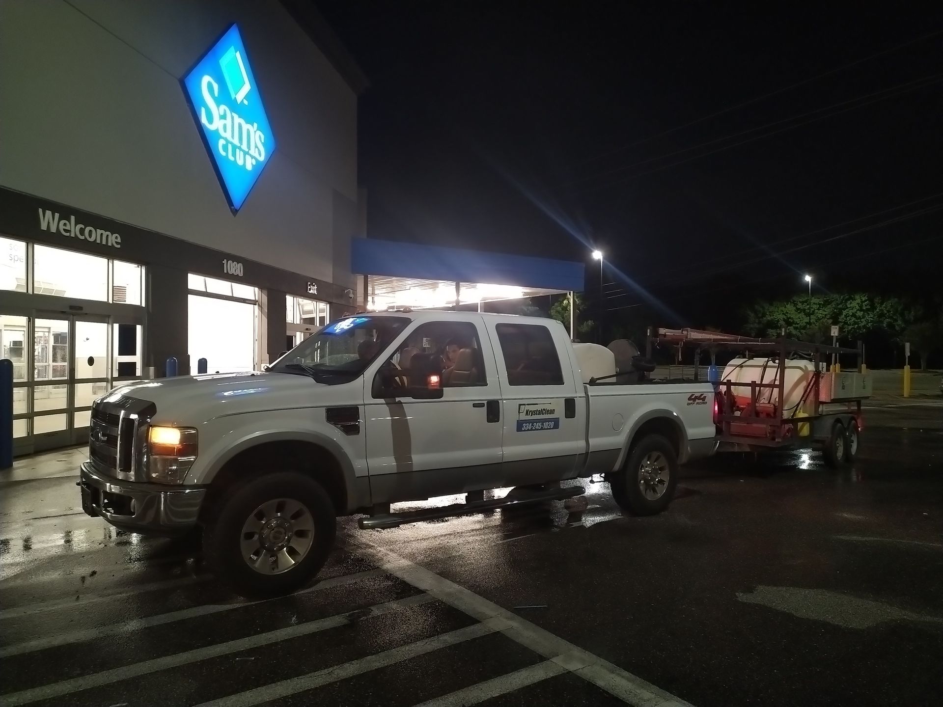 White pickup truck with a trailer parked outside a Cabela’s store at night.