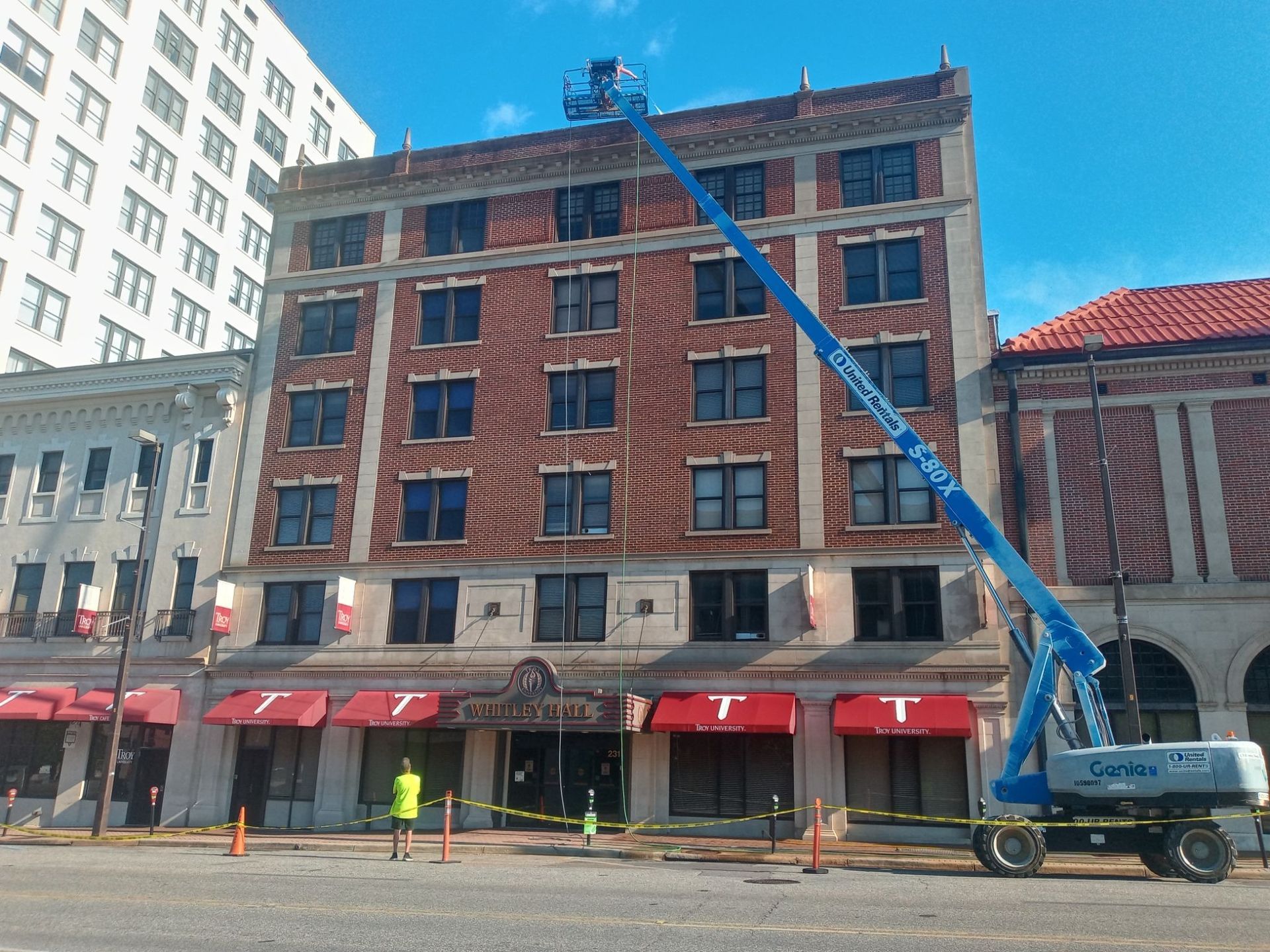 Multi-story historic brick building exterior cleaning with boom lift equipment in downtown area
