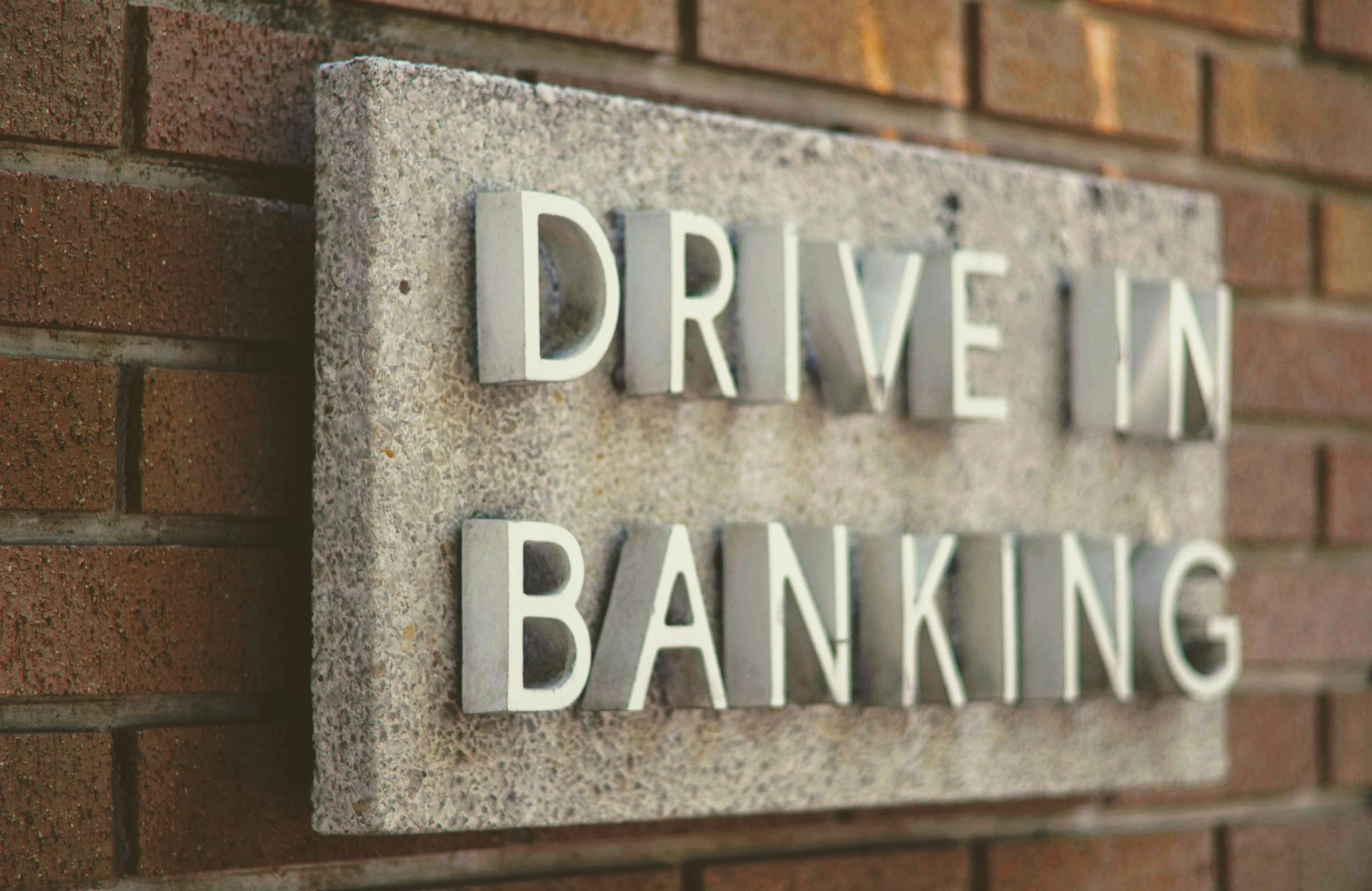 Drive-in banking sign on a brick building wall