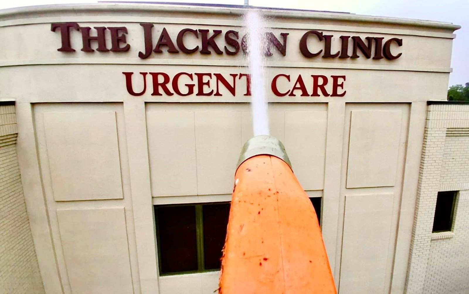 Commercial pressure washing in progress at an urgent care building, removing dirt and buildup from 
