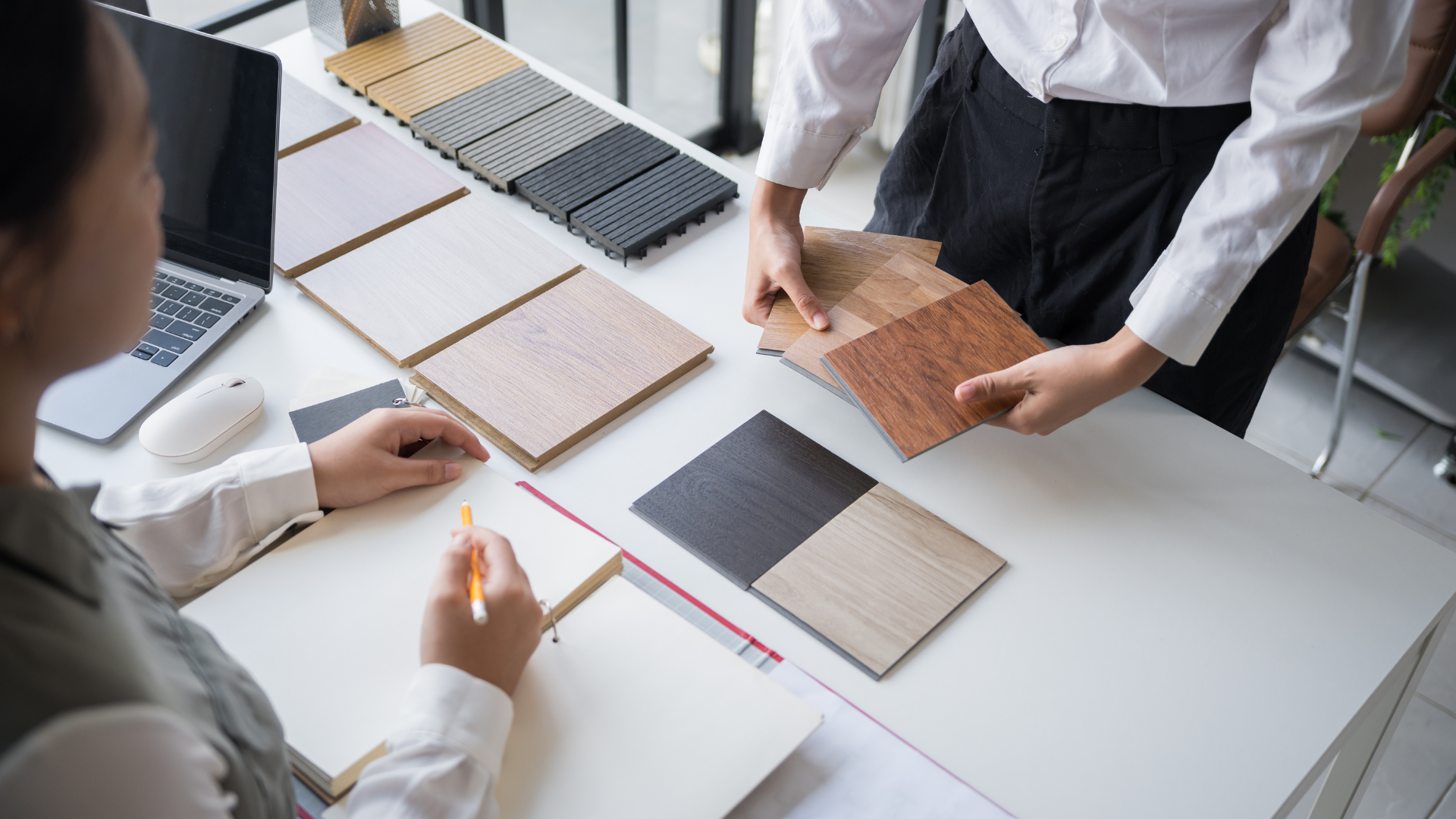 People reviewing fabric swatches and notebooks around a white table in a bright office.