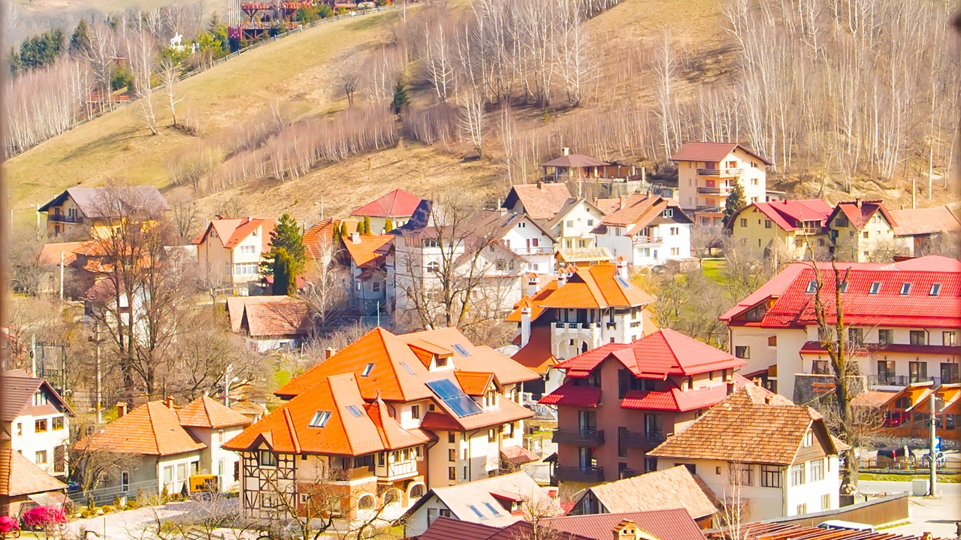 Colorful village with orange rooftops on a hillside in a mountainous landscape