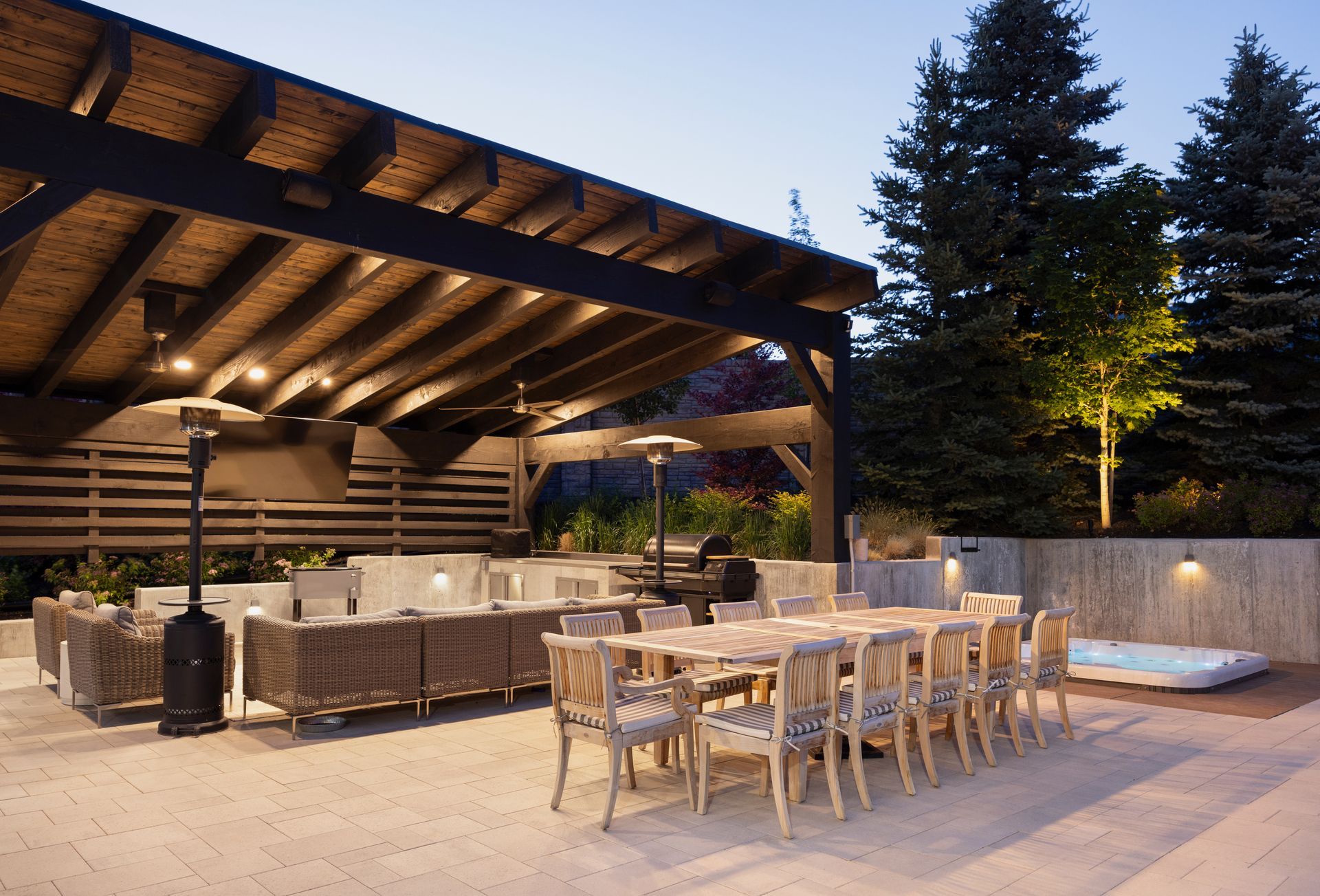 A stone patio with a rectangular swimming pool, a water feature, a waterslide tunnel, and tiered landscaping.