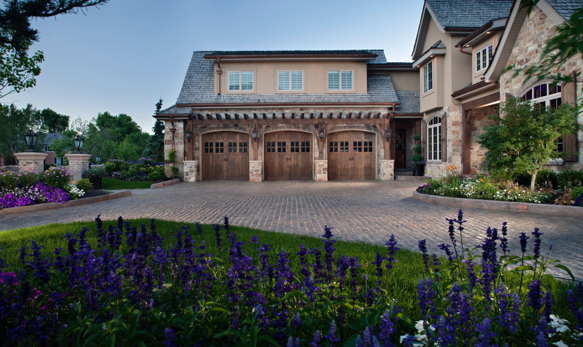 A tiered stone garden with a cascading waterfall, stone steps, and colorful flowers along a landscaped pathway.