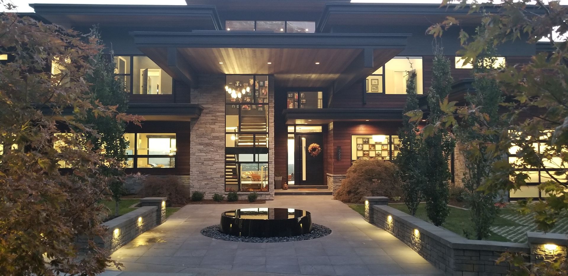 A stone patio with a rectangular swimming pool, a water feature, a waterslide tunnel, and tiered landscaping.