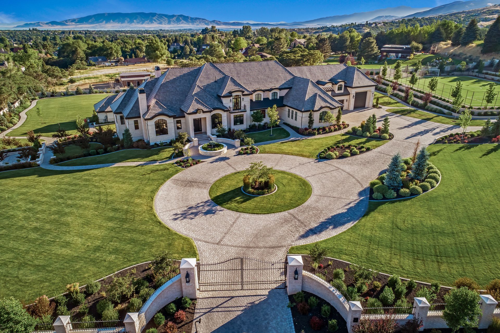 A stone patio with a rectangular swimming pool, a water feature, a waterslide tunnel, and tiered landscaping.