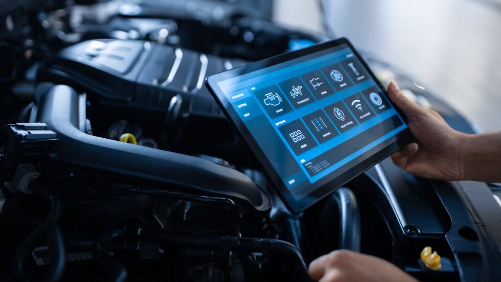 A Person is Holding a Tablet in Front of a Car Engine — Ballina Automatics in Ballina, NSW