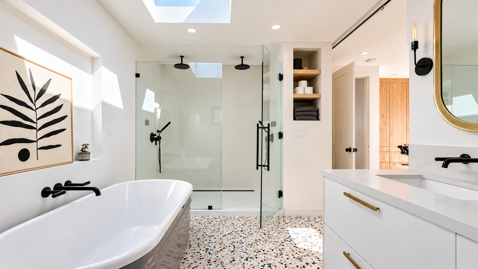 Bright modern bathroom with freestanding tub, glass shower, skylight, and white vanity with gold accents