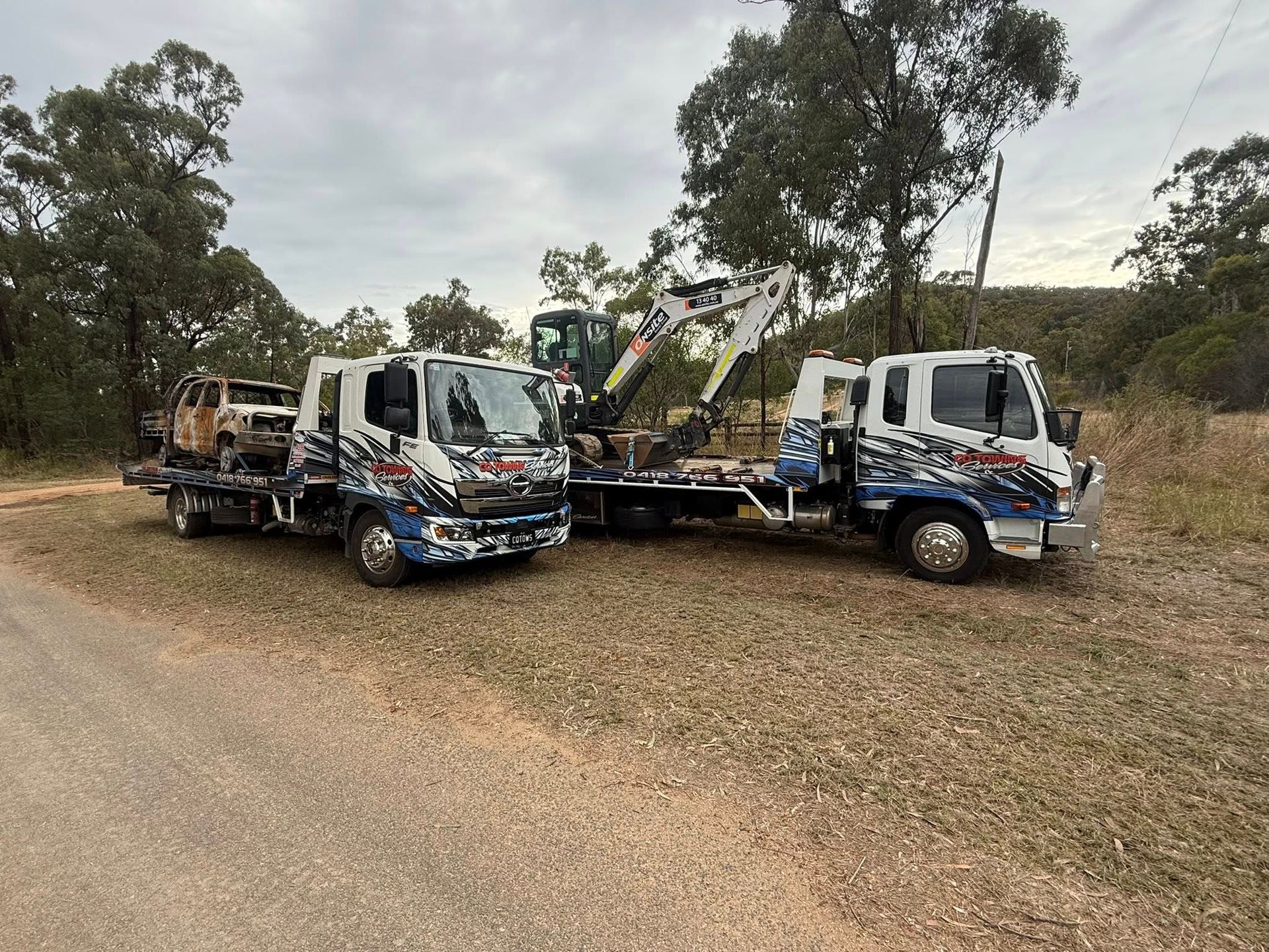 Two Flatbed Tow Trucks Parked on A Dirt Road — Cq Towing Services In Rockhampton City, QLD