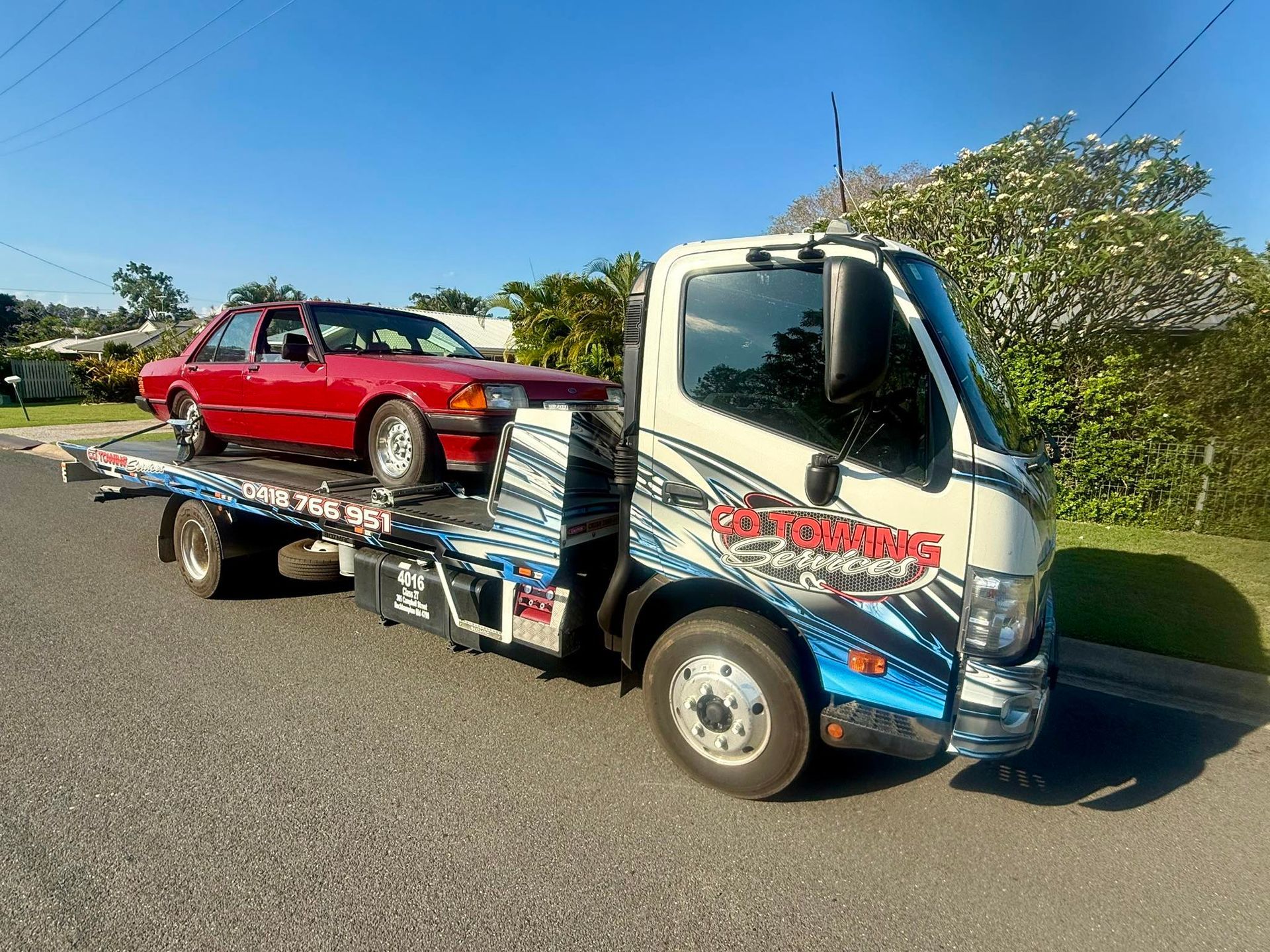 Red Car on A Tow Truck on A Street, Sunny Day — Cq Towing Services In Rockhampton City, QLD
