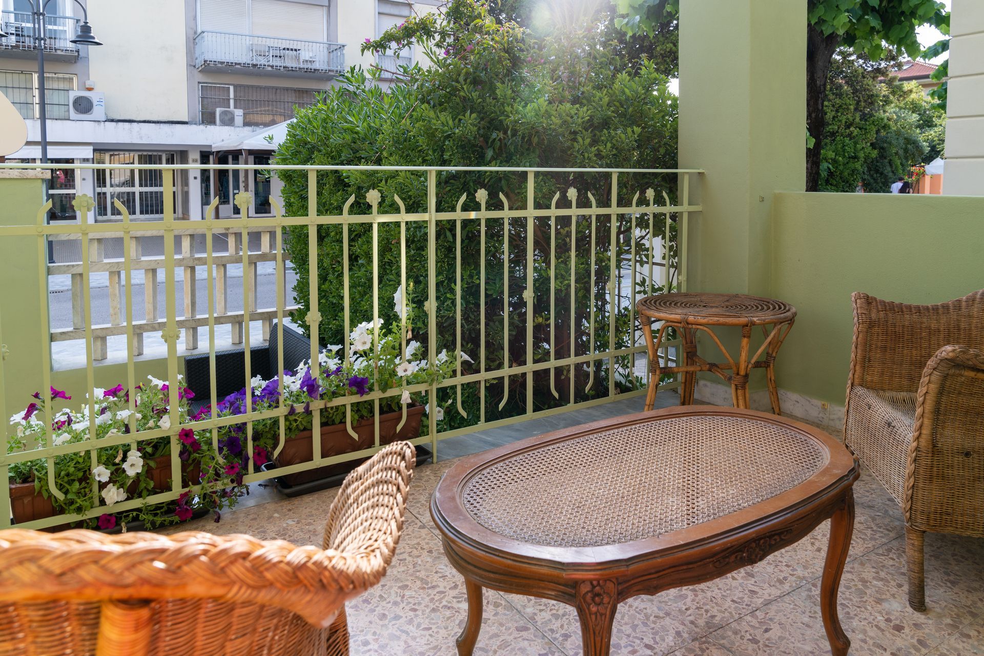 Balcony with wicker furniture, flower boxes, and a metal railing.
