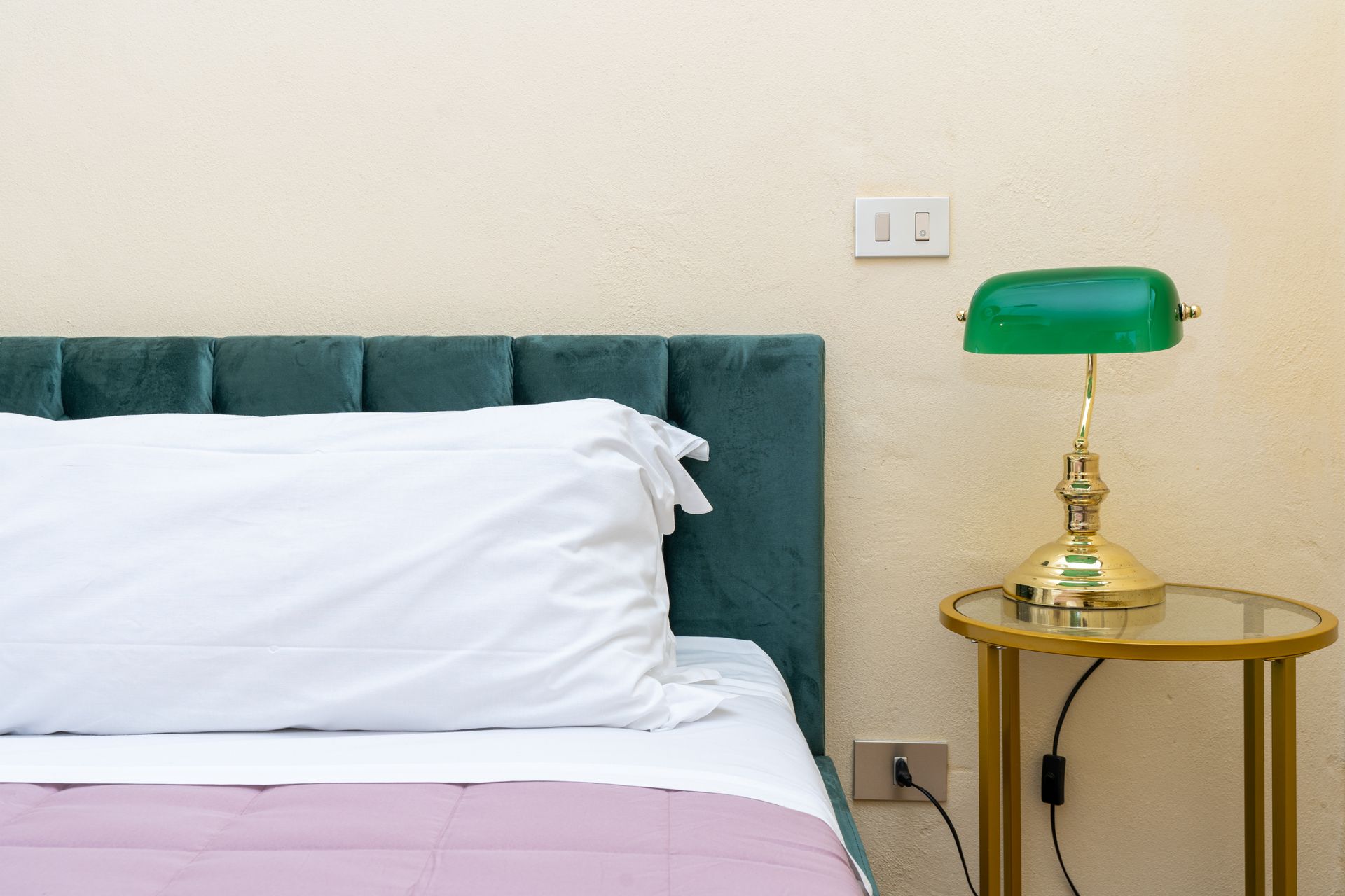 Bed with white pillow, green headboard, bedside table with green lamp.