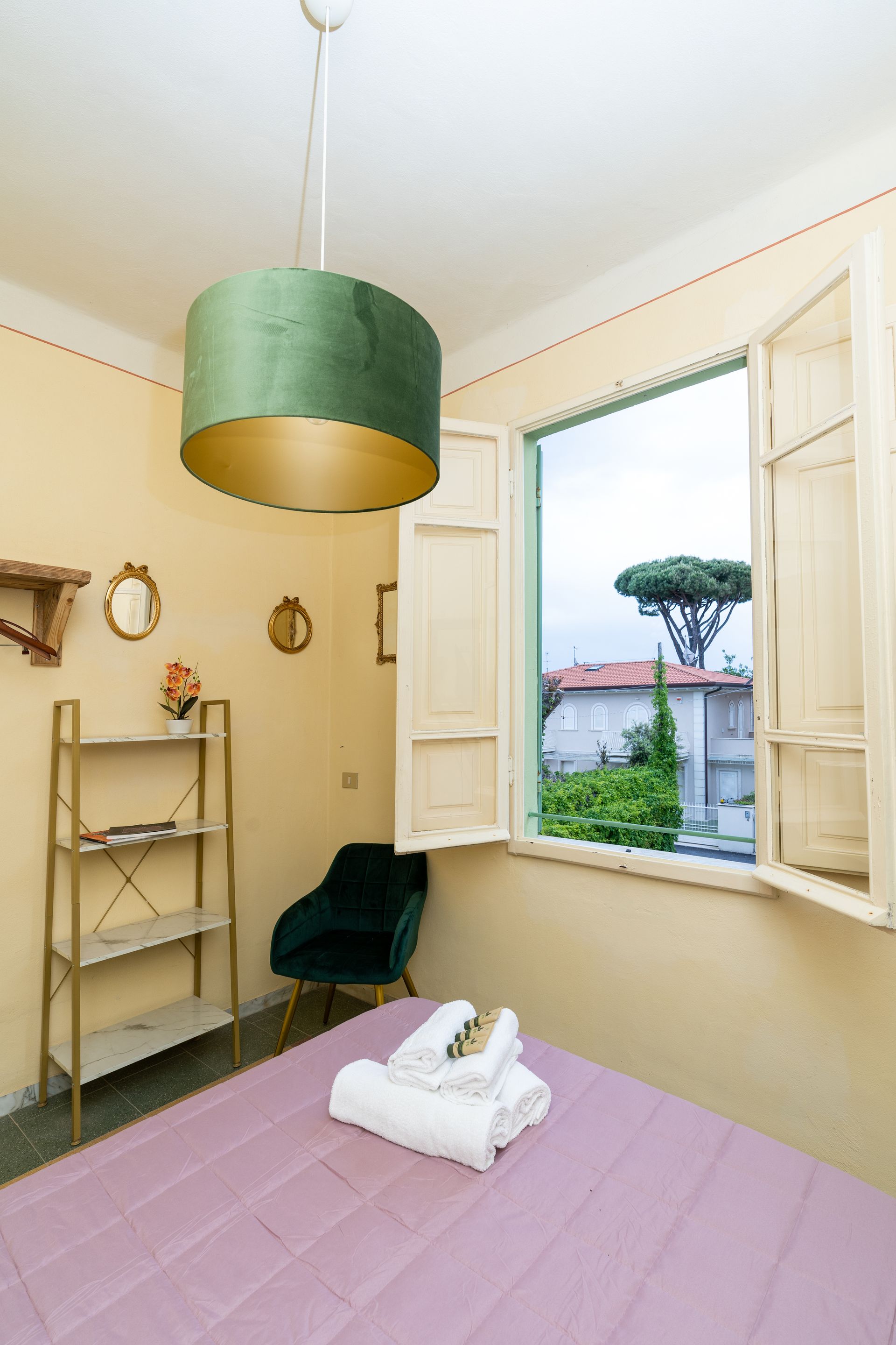 Bedroom with bed, open window, and green pendant lamp.