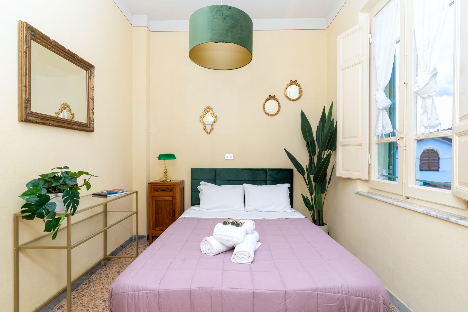 Bedroom with bed, nightstand, gold accents, green decor, and window.