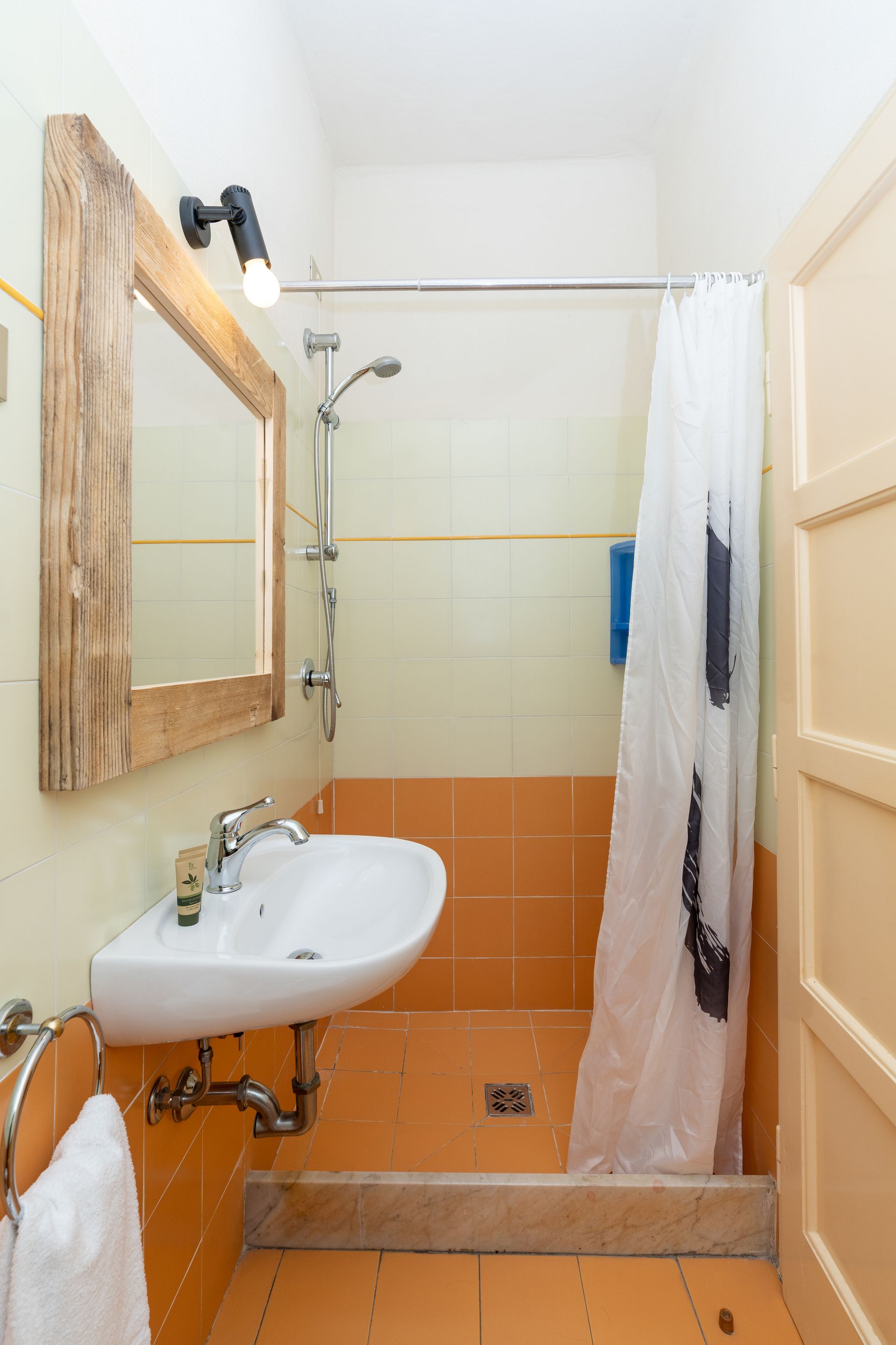 Bathroom with orange tiles, white sink, and shower curtain.