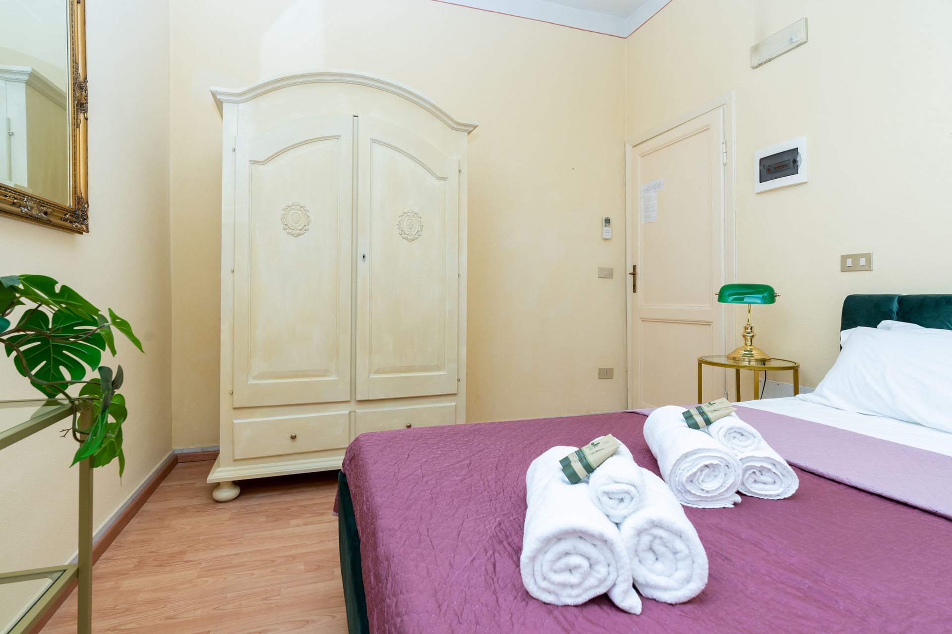 Bedroom with bed, white wardrobe, and rolled towels.