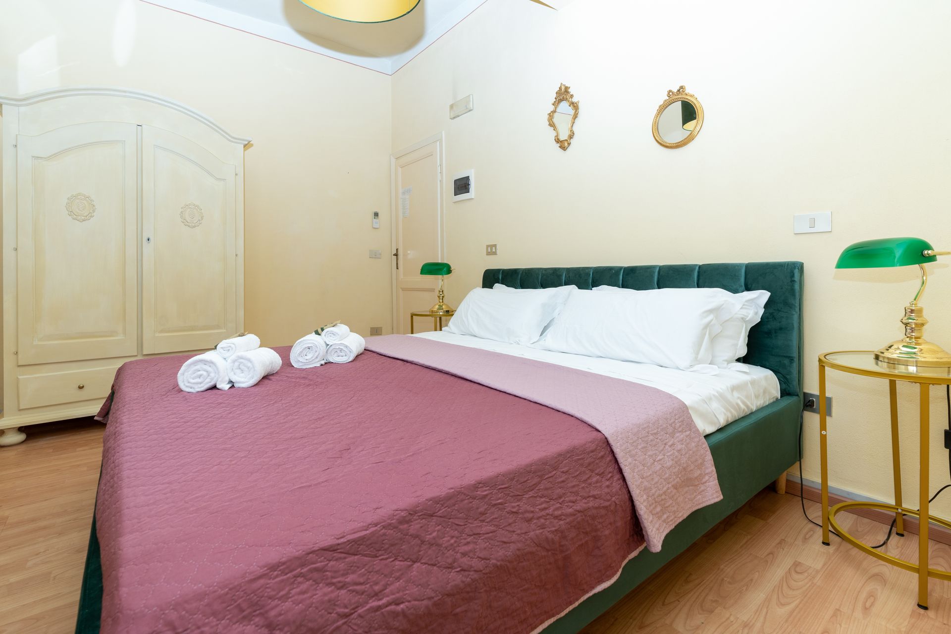 Bedroom with bed, wardrobe, two lamps, and decorative mirrors.