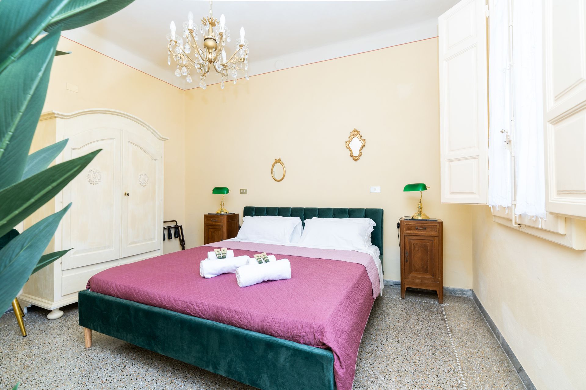 Bedroom with bed, wardrobe, window, chandelier, and bedside tables.