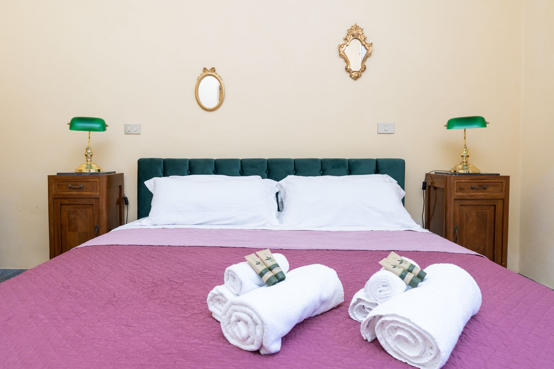 Bedroom with double bed, nightstands, lamps, and decorative mirrors on wall.