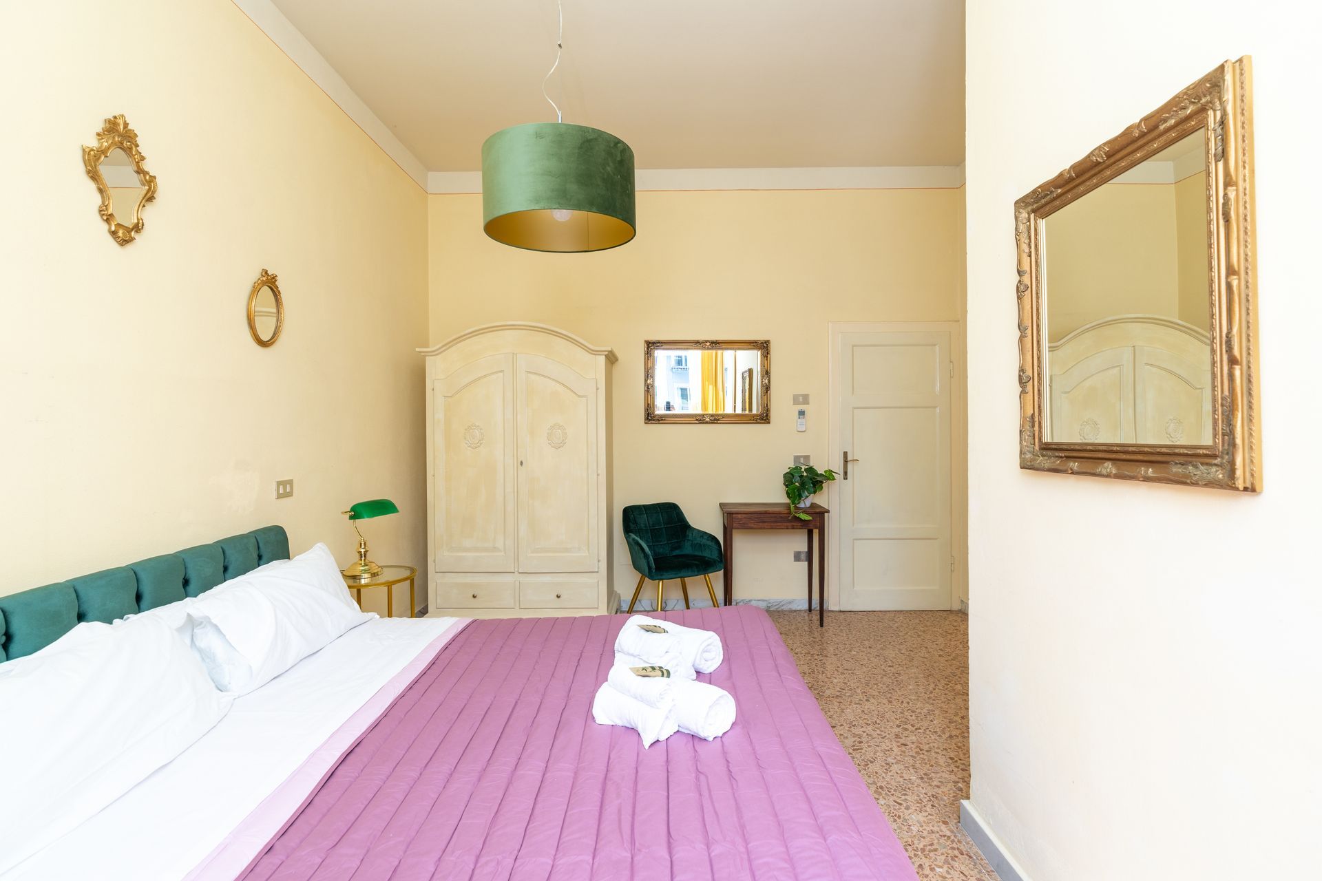 Bedroom with a bed, dresser, chair, mirror, and decorative gold framed artwork.