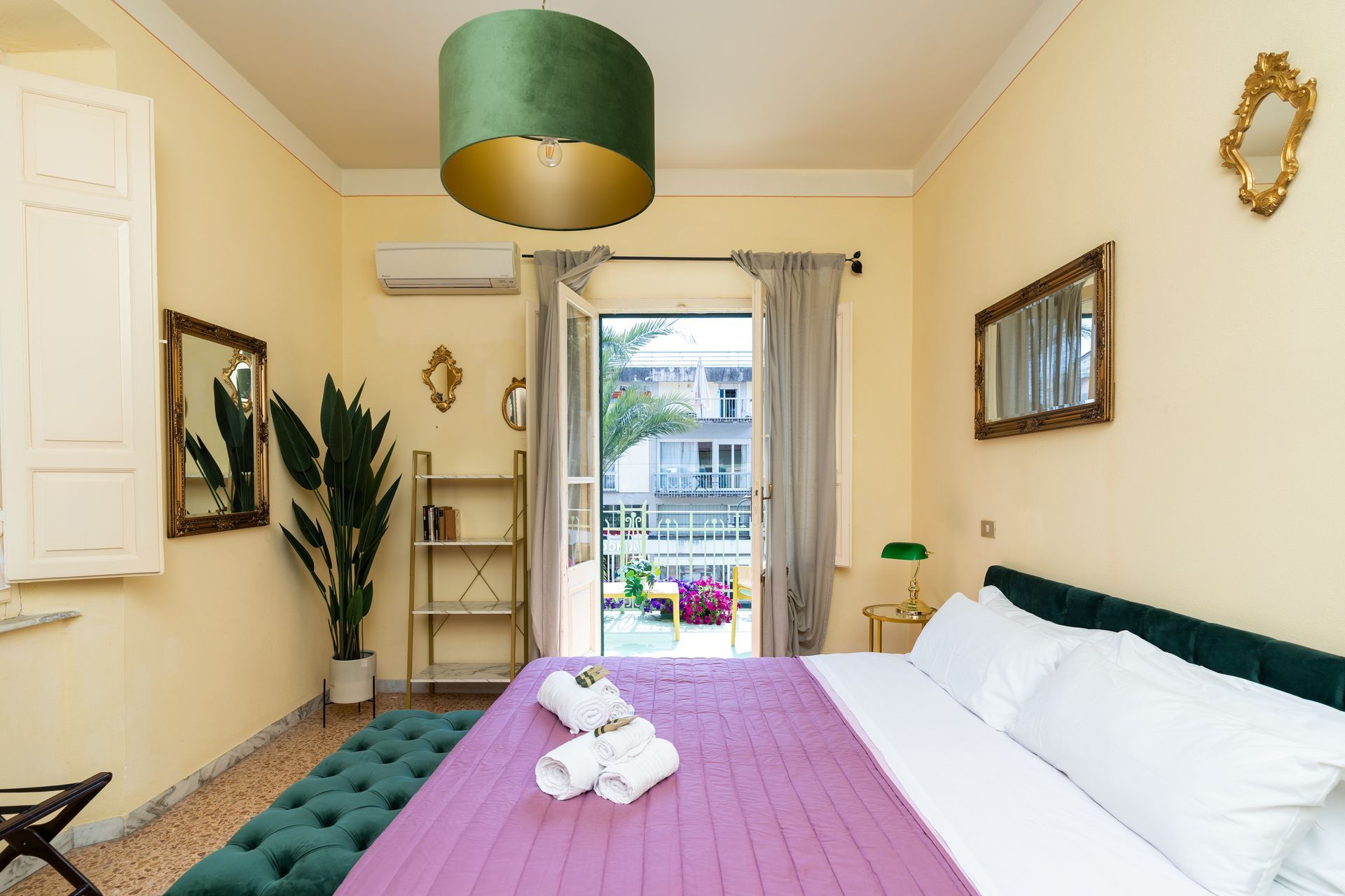 Bedroom with a large bed, open balcony, green and gold decor.