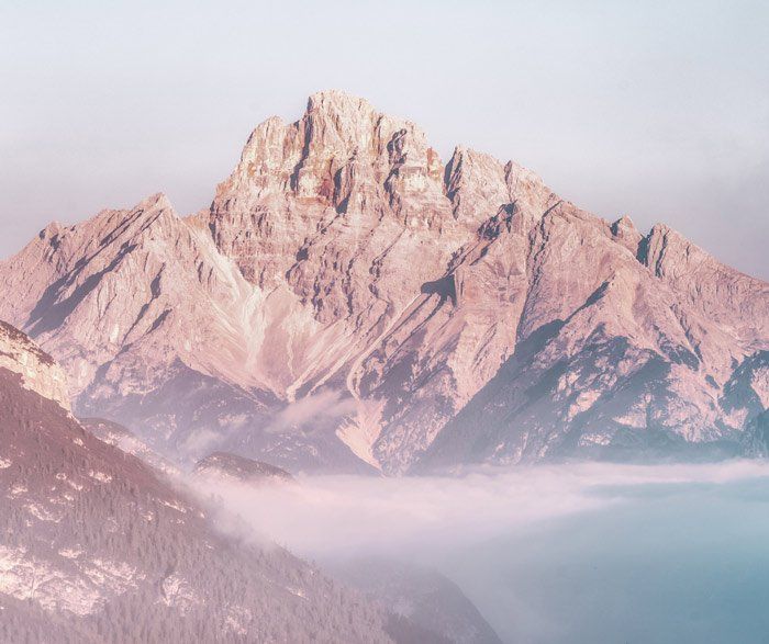 a mountain covered in fog with a lake in the foreground .