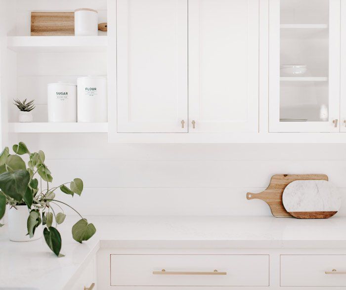 A kitchen with white cabinets and a cutting board on the counter.