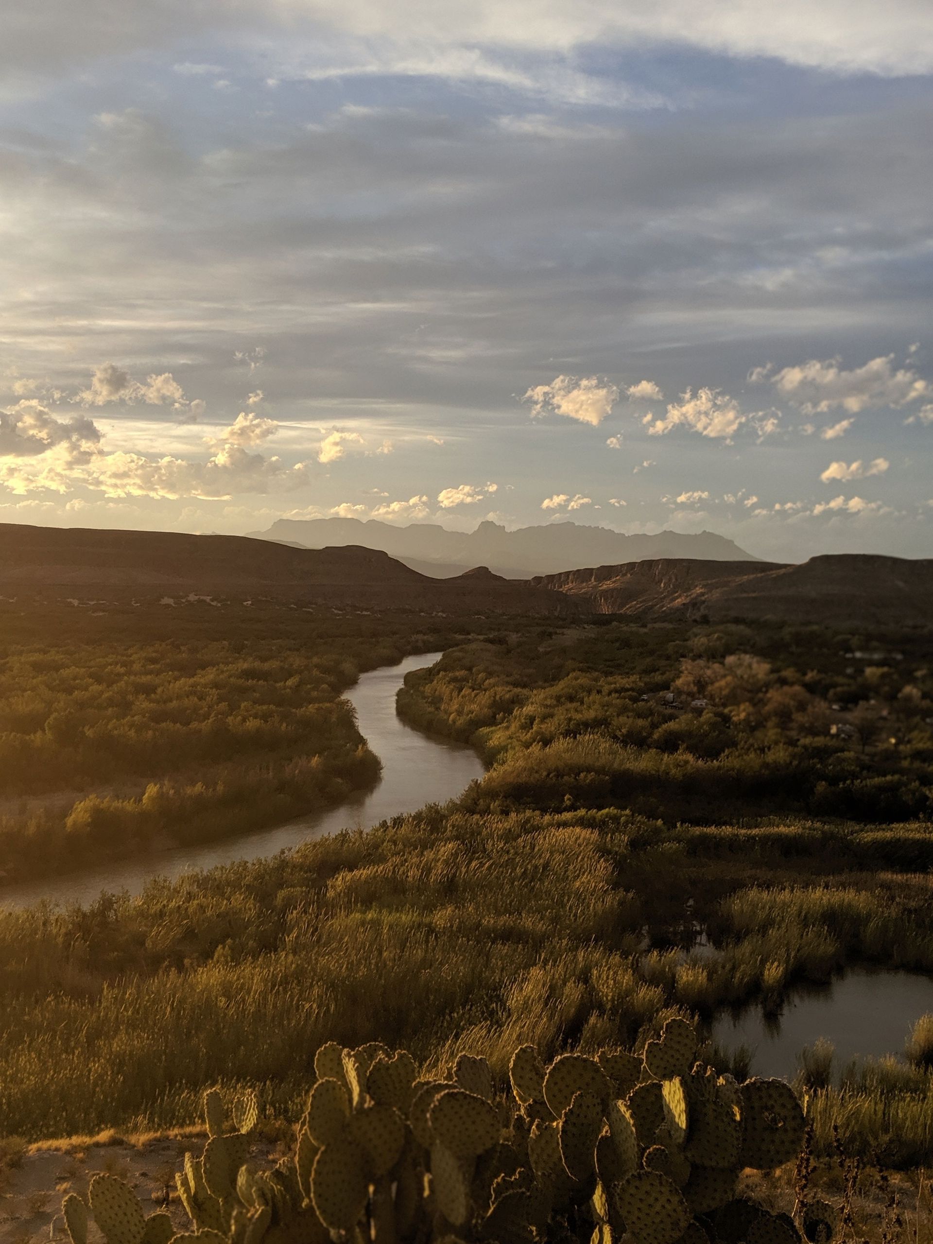 Golden sunset over a winding river through green hills and clouds