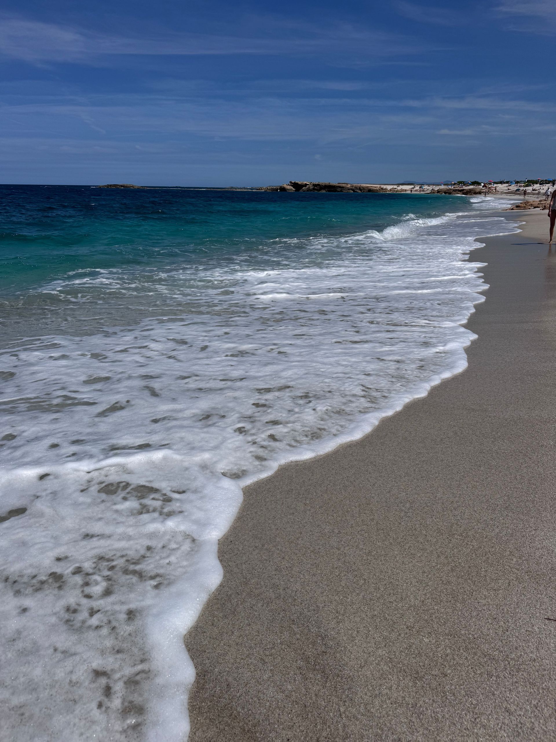 Waves washing onto a sandy beach under a clear blue sky