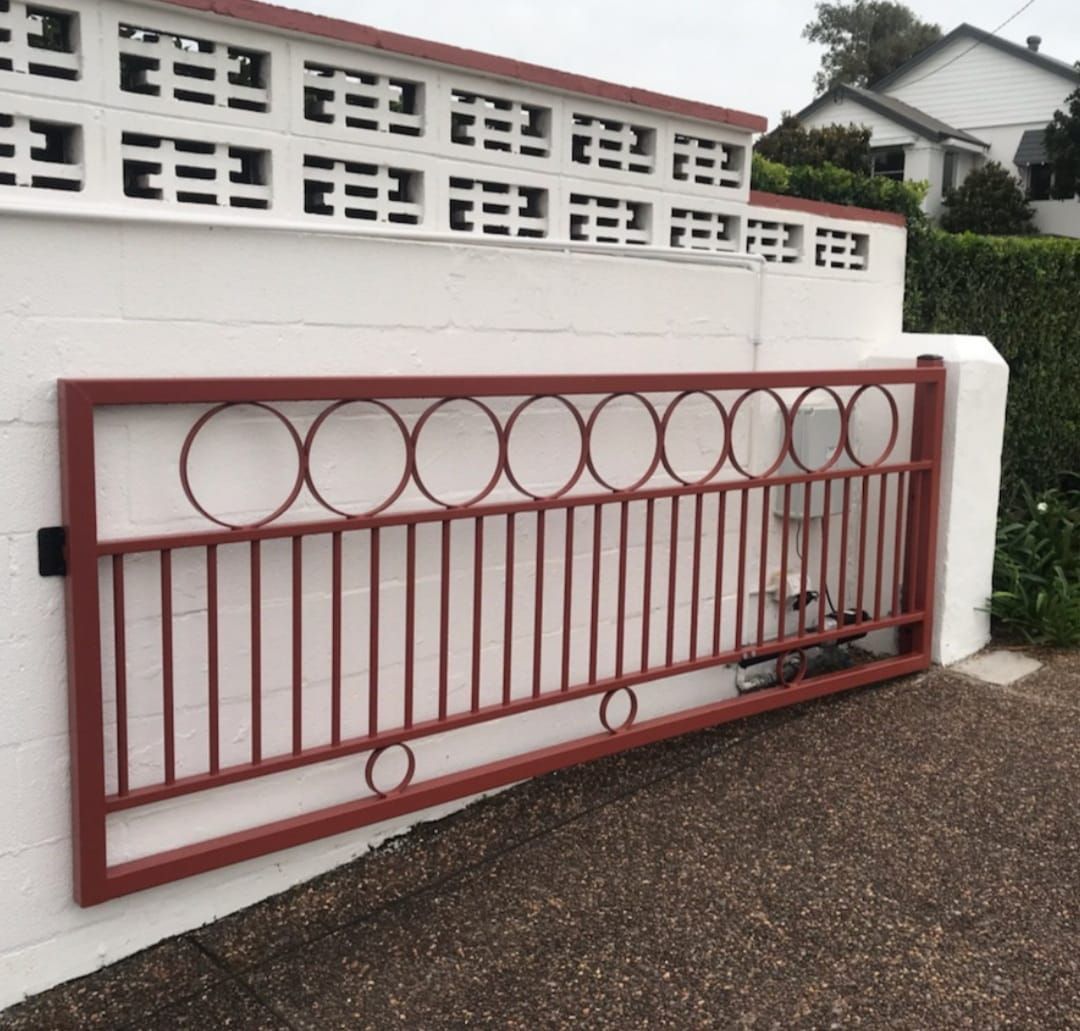 Red Sliding Gate Against A White Wall — Decorative Aluminium Works In Lake Macquarie, NSW