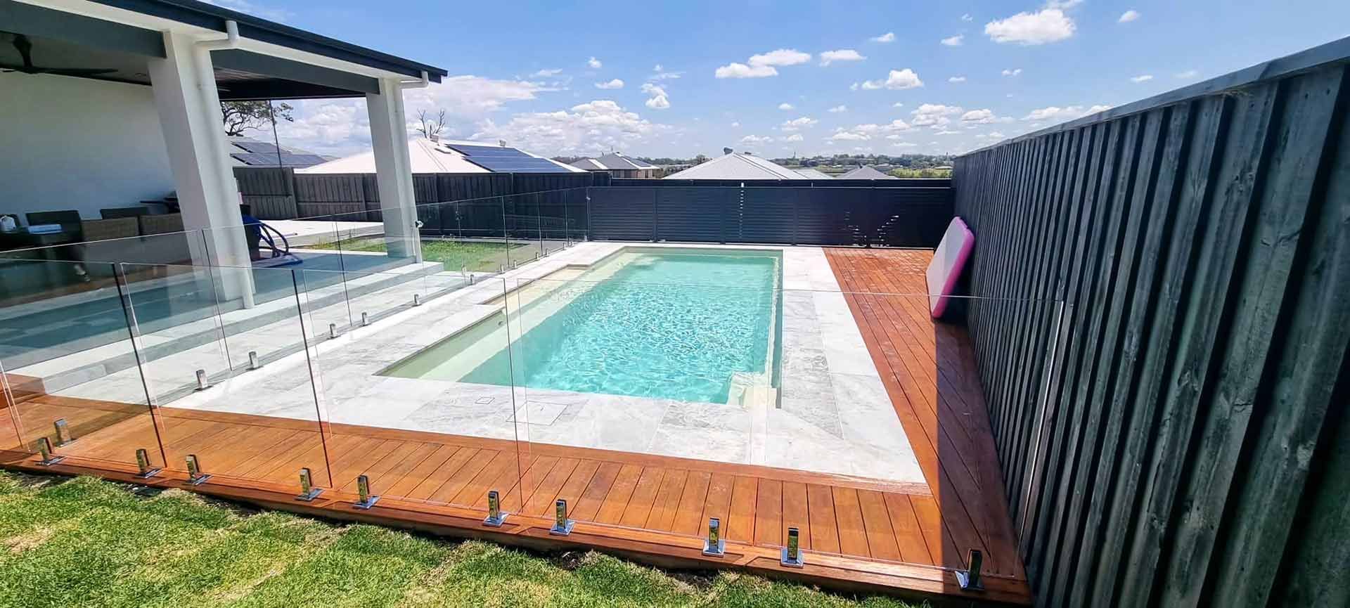 Large Swimming Pool In The Backyard Of A House With Glass Fencing On Two Sides — Decorative Aluminium Works In Cardiff, NSW