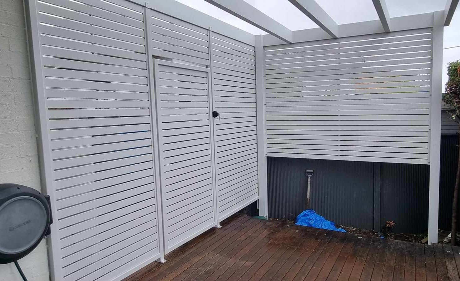 White Fence Is Sitting On Top Of A Wooden Deck — Decorative Aluminium Works In Cardiff, NSW