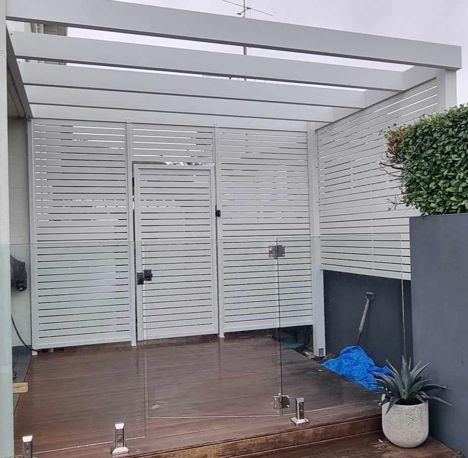 Pergola With A White Fence And A Glass Door — Decorative Aluminium Works In Cardiff, NSW