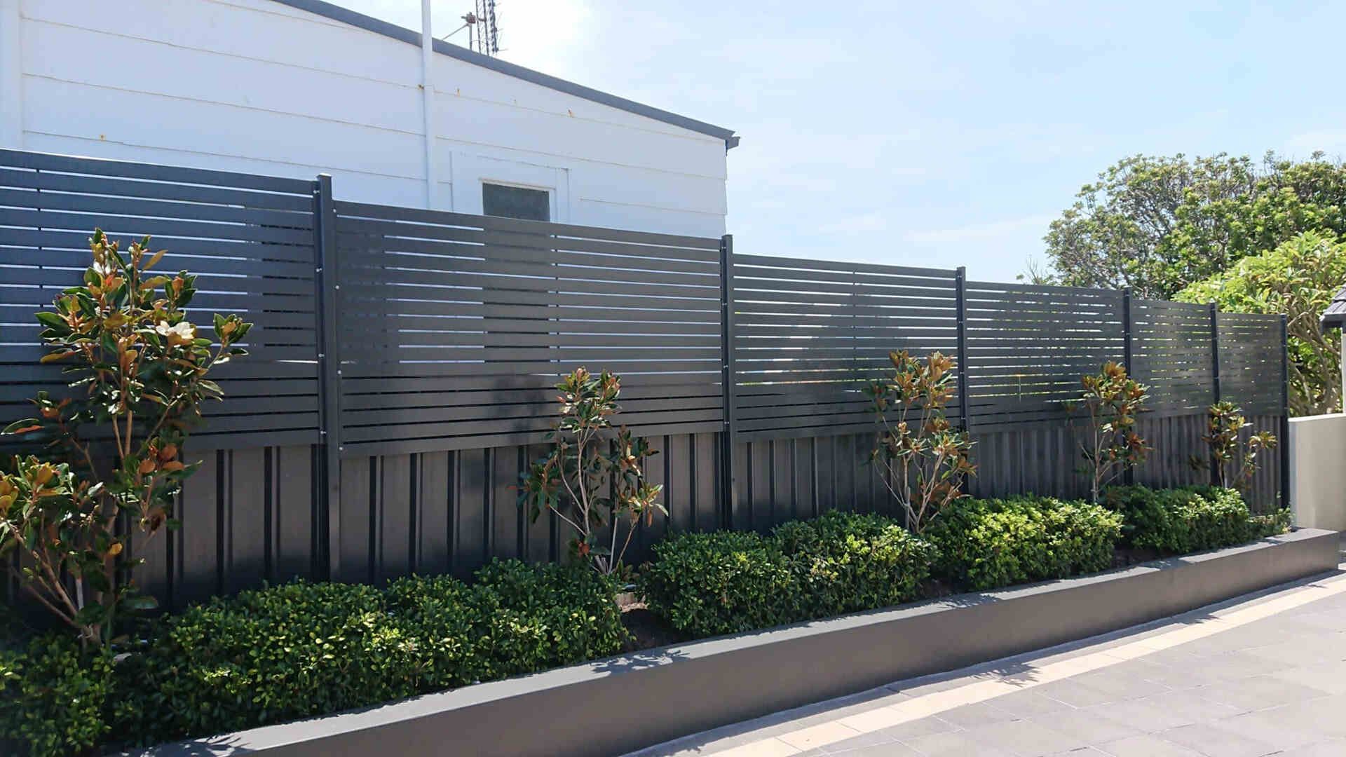 Stylised Fence With A Lot Of Plants In Front Of A Residential Building — Decorative Aluminium Works In Cardiff, NSW