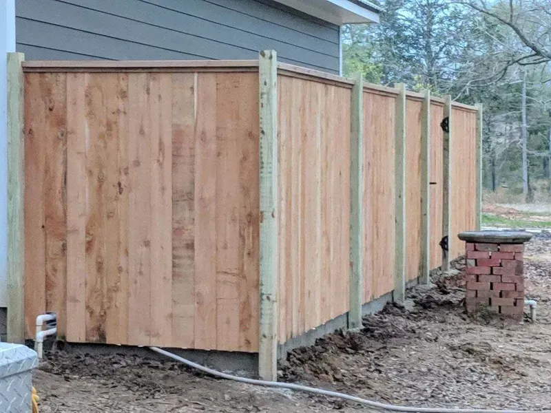 Wooden fence alongside a building. Brown planks between light green posts.