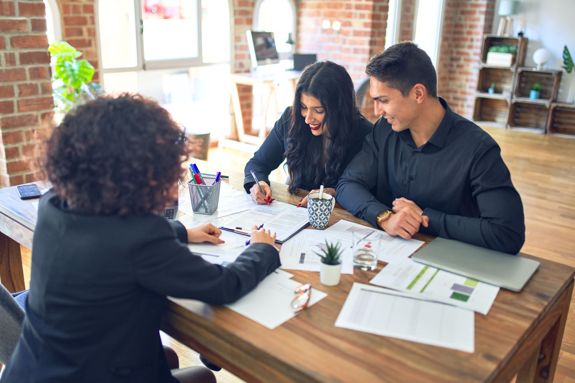 A man and woman are sitting at a table talking to a woman.