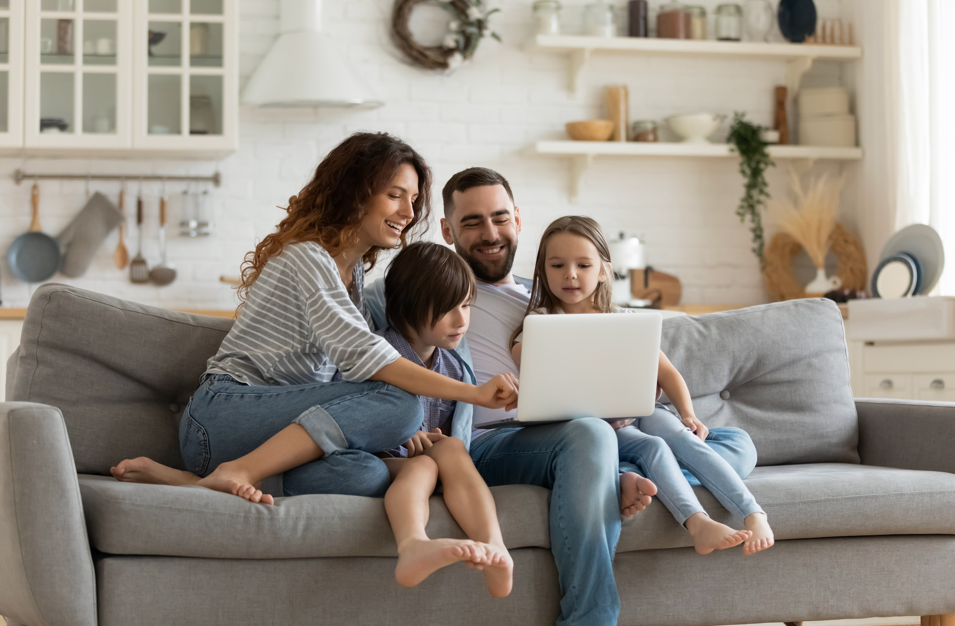 A family is sitting on a couch using a laptop computer.