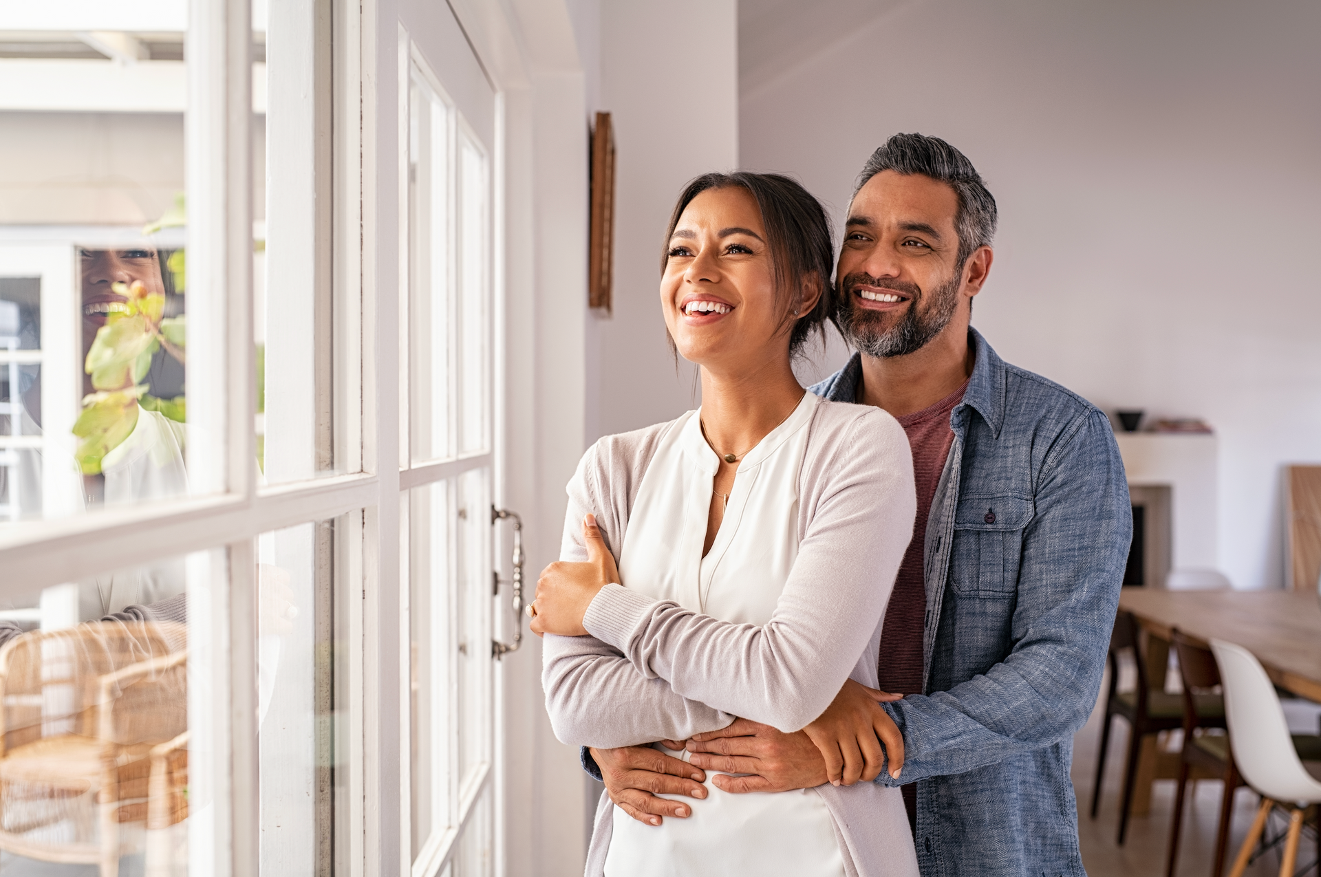 A man and a woman are standing next to each other in front of a window.