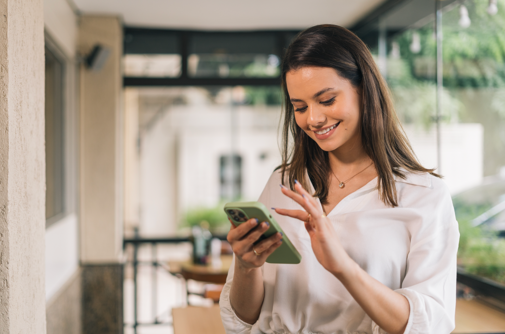 A woman is smiling while looking at her cell phone.