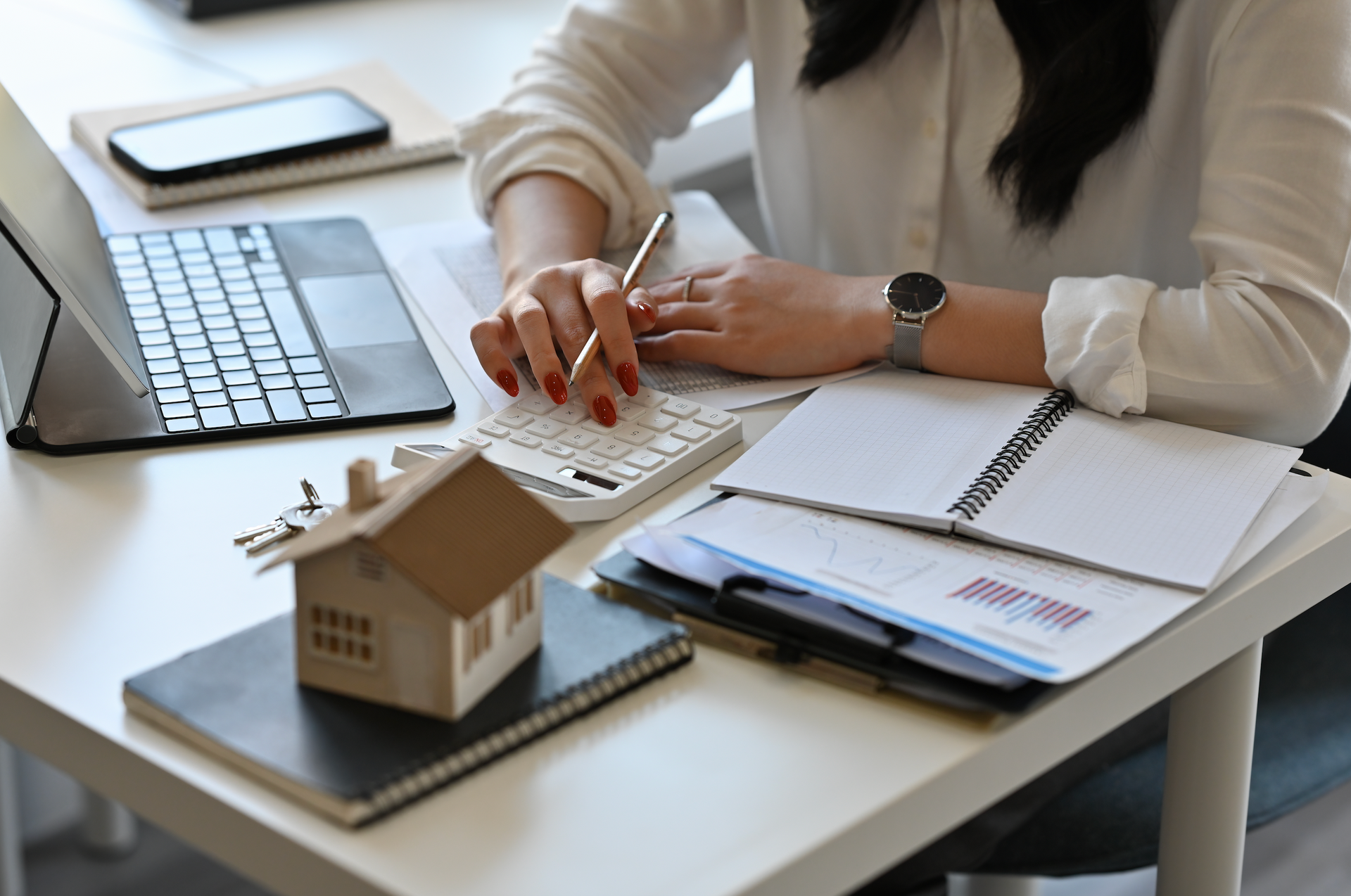 A woman is sitting at a desk using a laptop and a calculator.
