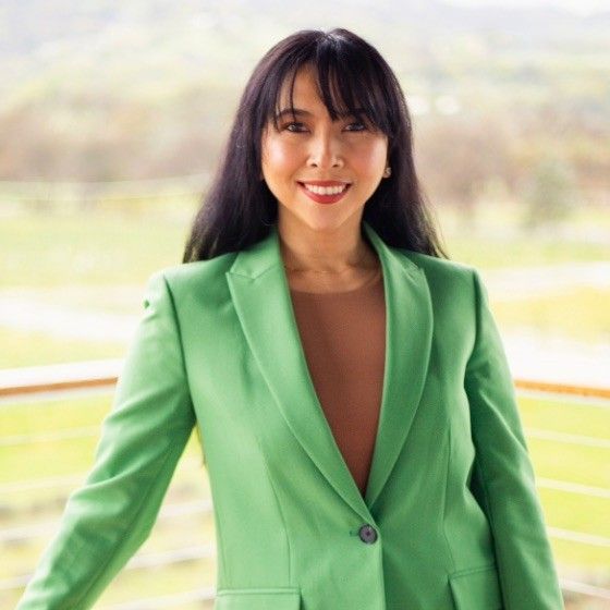 A woman in a green jacket is smiling for the camera