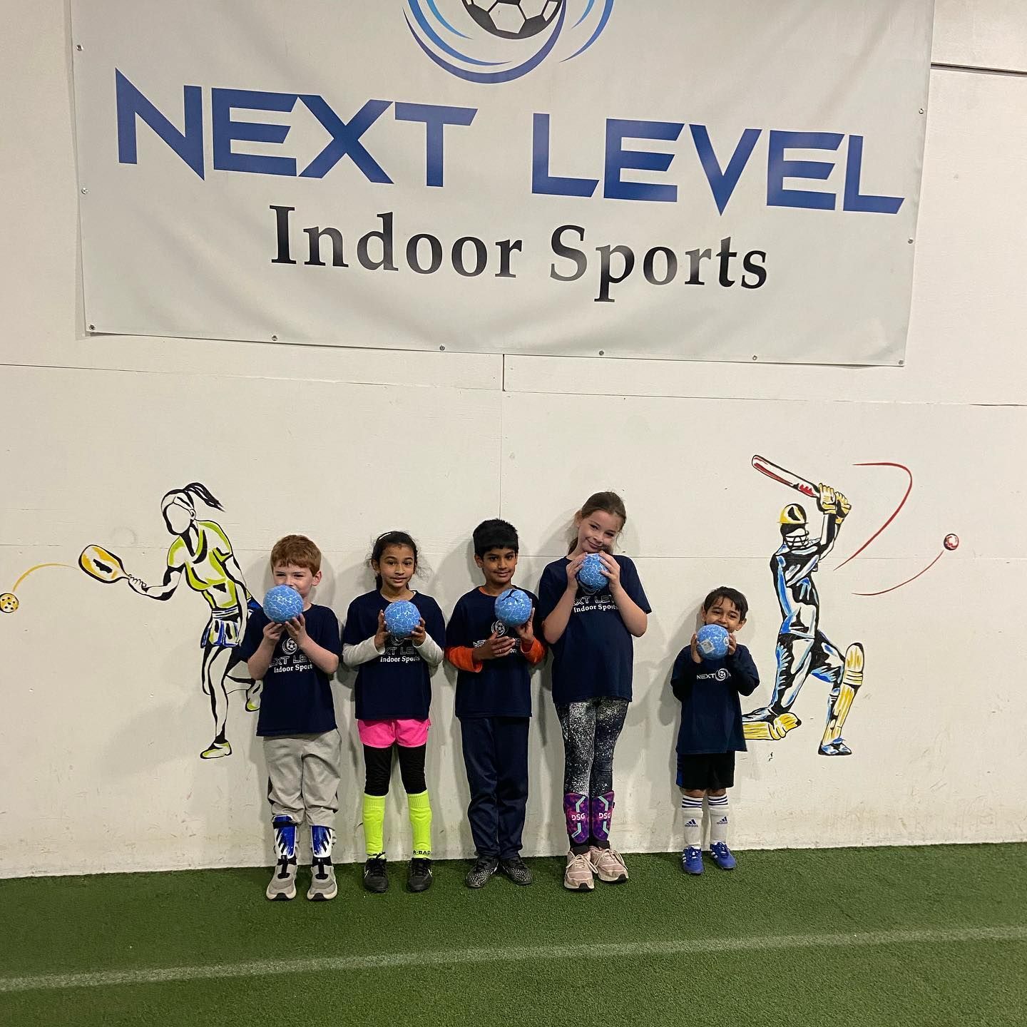A group of children standing in front of a sign that says next level indoor sports
