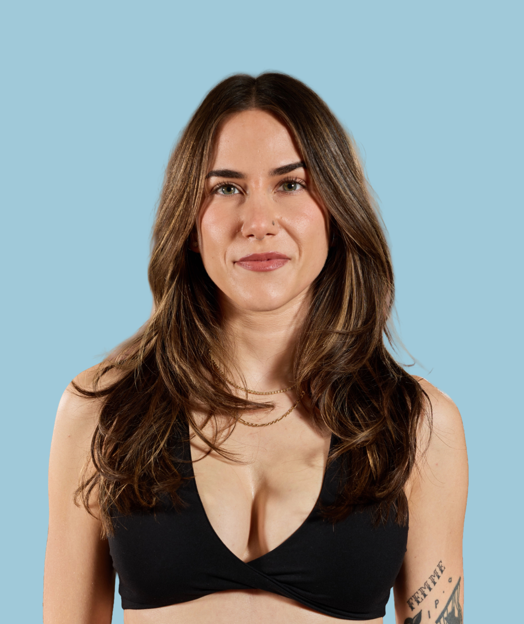 Closeup of a smiling woman with long brown hair with a bright blue background.