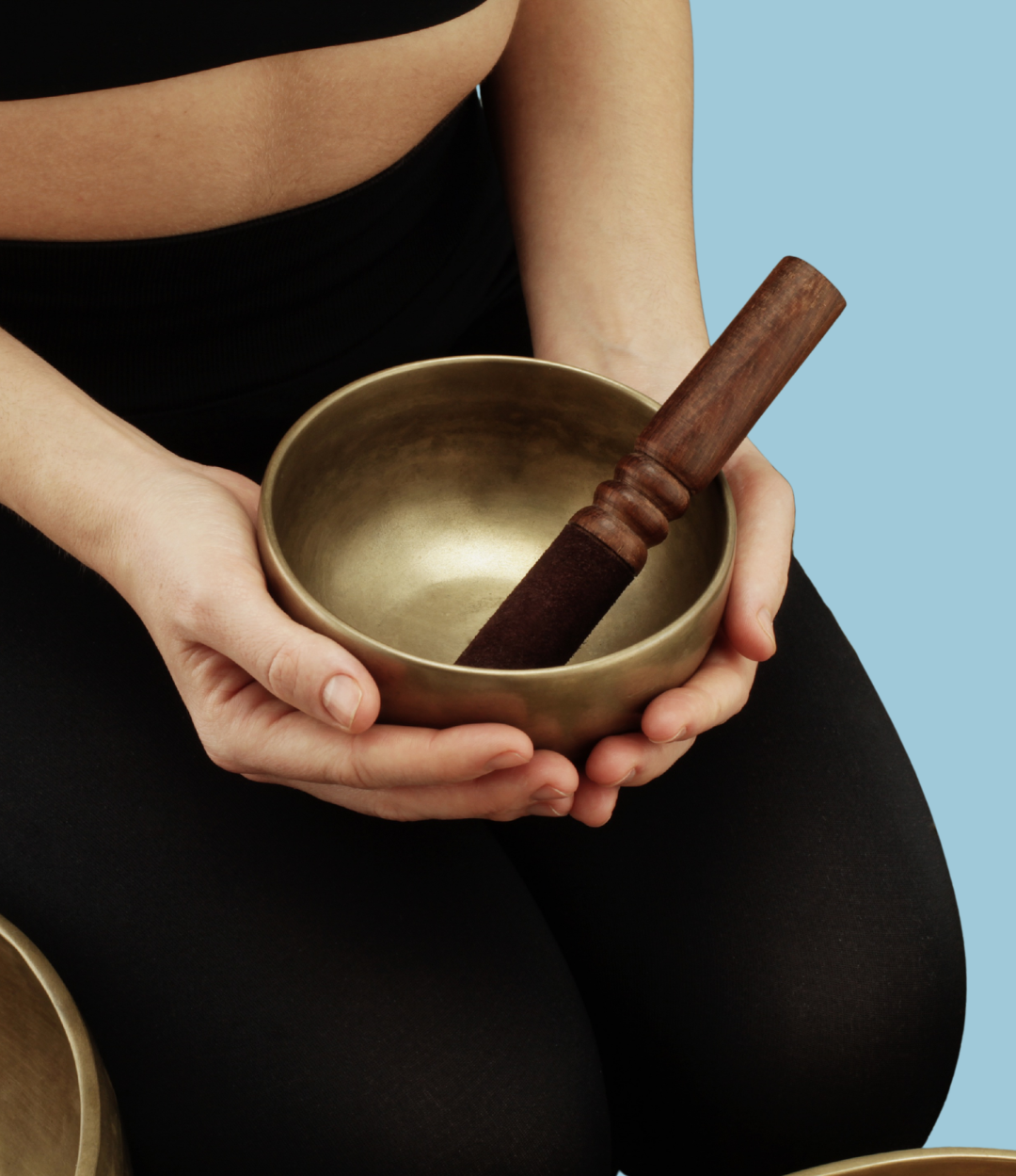 Picture of a woman in a black yoga set preparing for a sound bath experience.